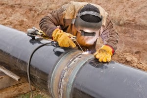 Welder welding pipeline without using primers. HinderRUST S4.0 and HinderRUST for Metal Fabrication are Weld-Thru Approved.